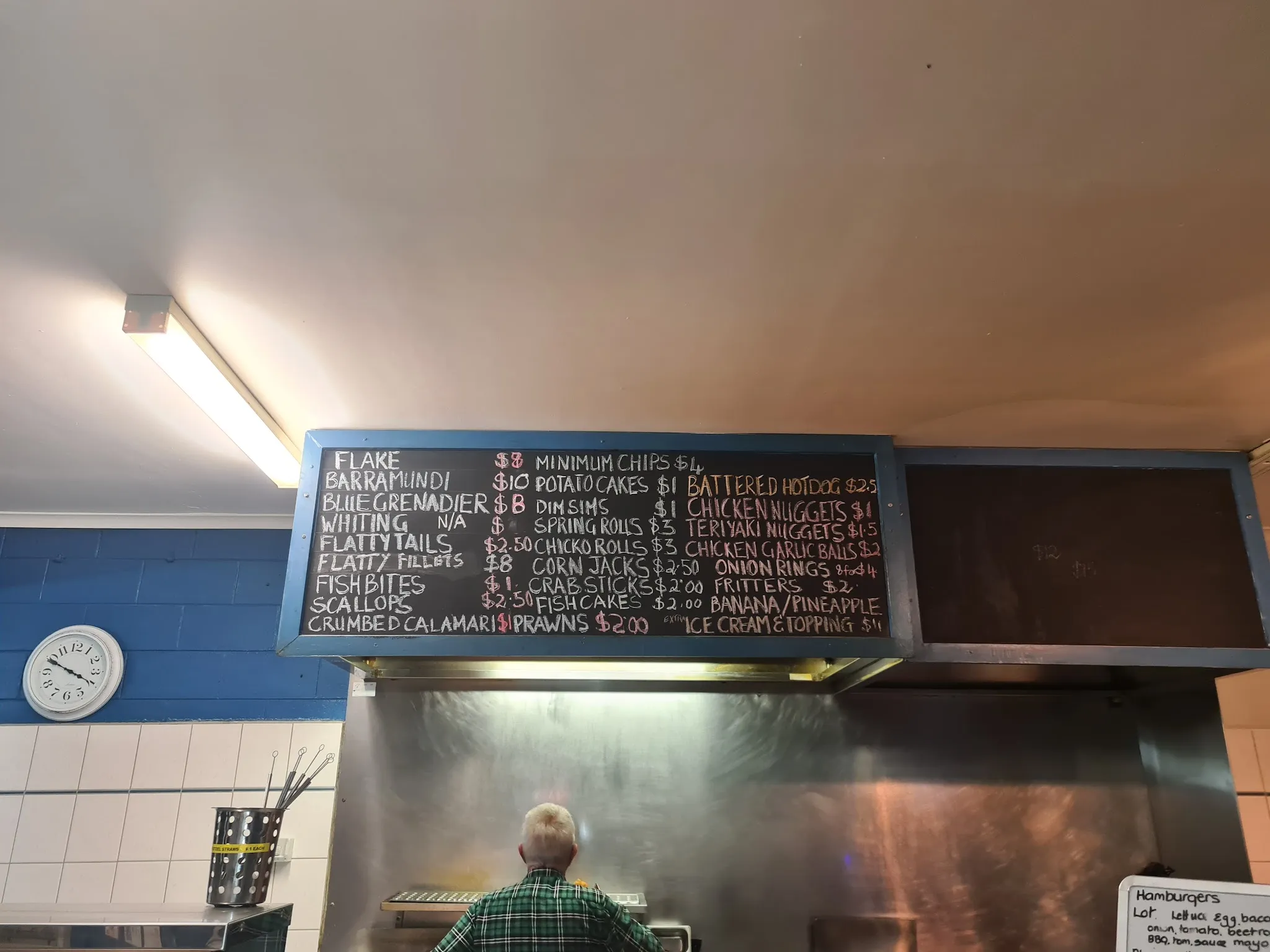 Chalkboard menu on the wall with a staff member at the counter