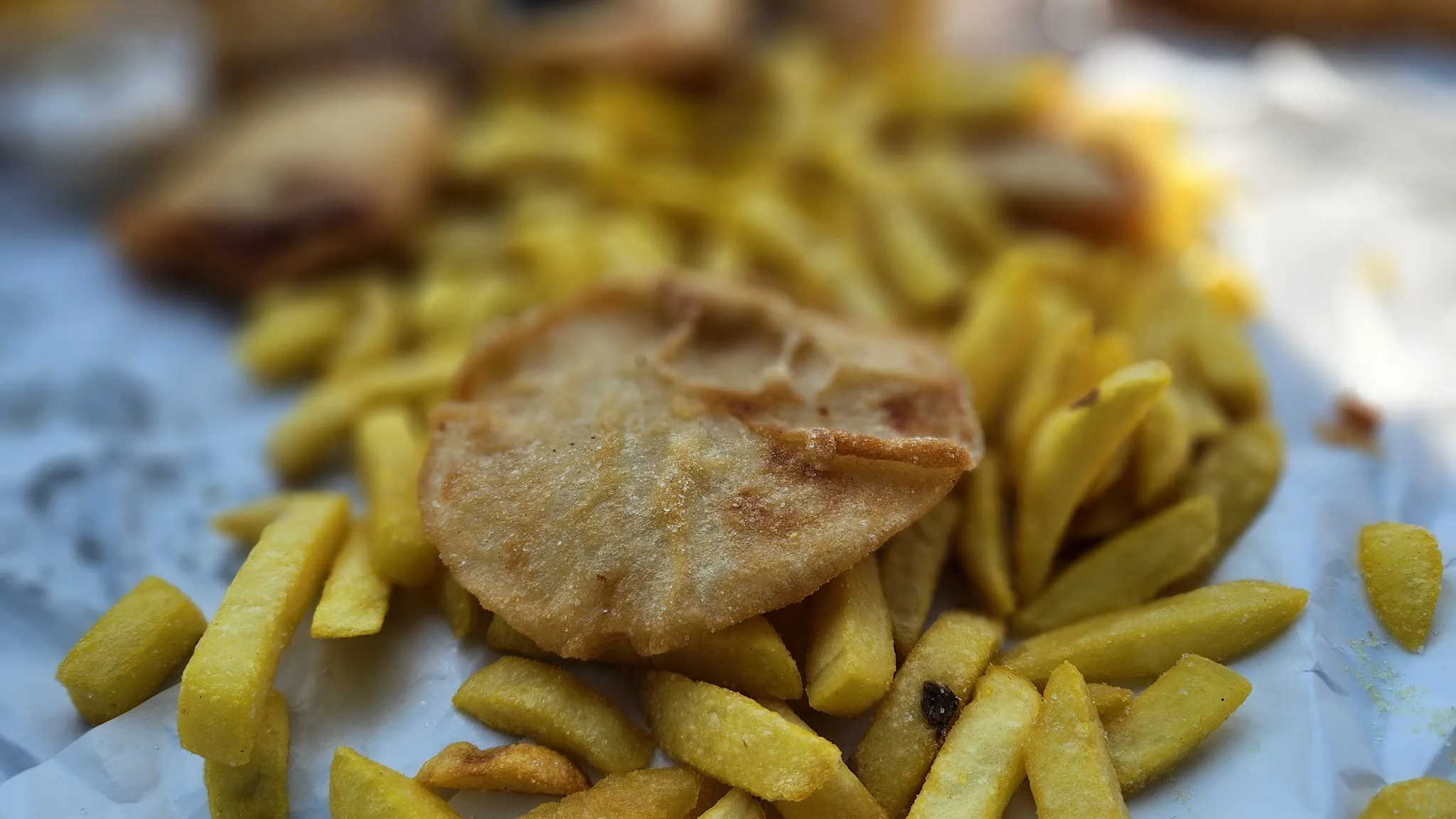 Golden potato cake and chips on white paper